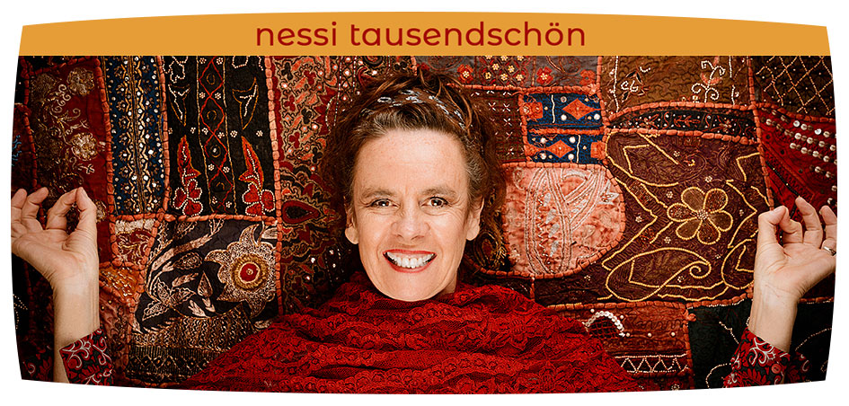 Frau stehend und laechelnd vor Wandteppich